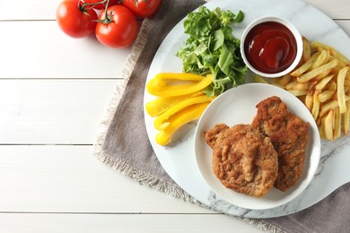 Photo of Tasty schnitzels served with potato fries, ketchup and vegetables on white wooden table, flat lay. Space for text