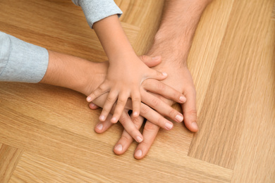 Photo of Happy family holding hands on wooden background, closeup