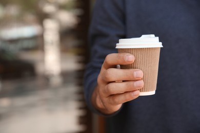 Man with takeaway coffee cup outdoors, closeup