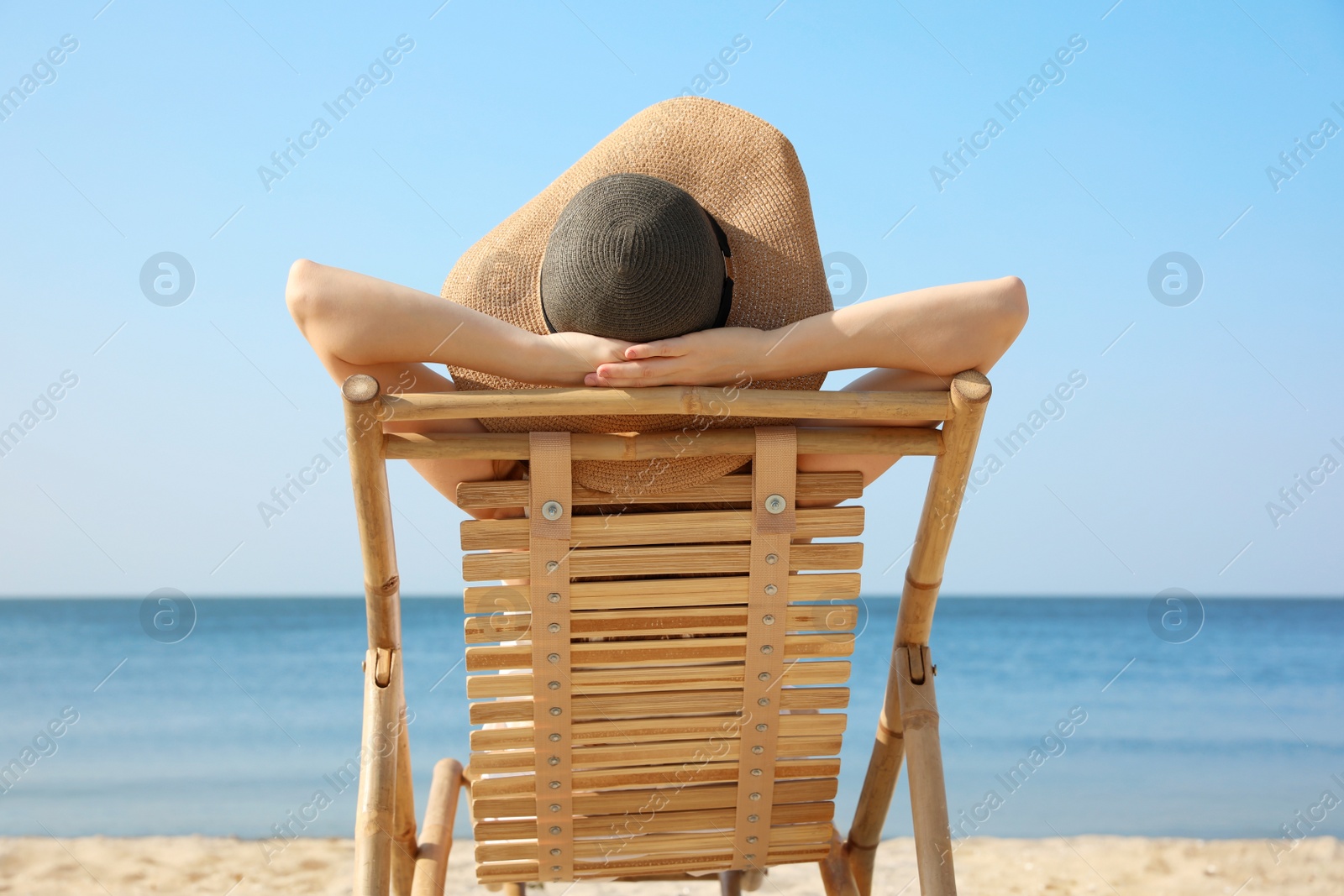 Photo of Young woman relaxing in deck chair on sandy beach