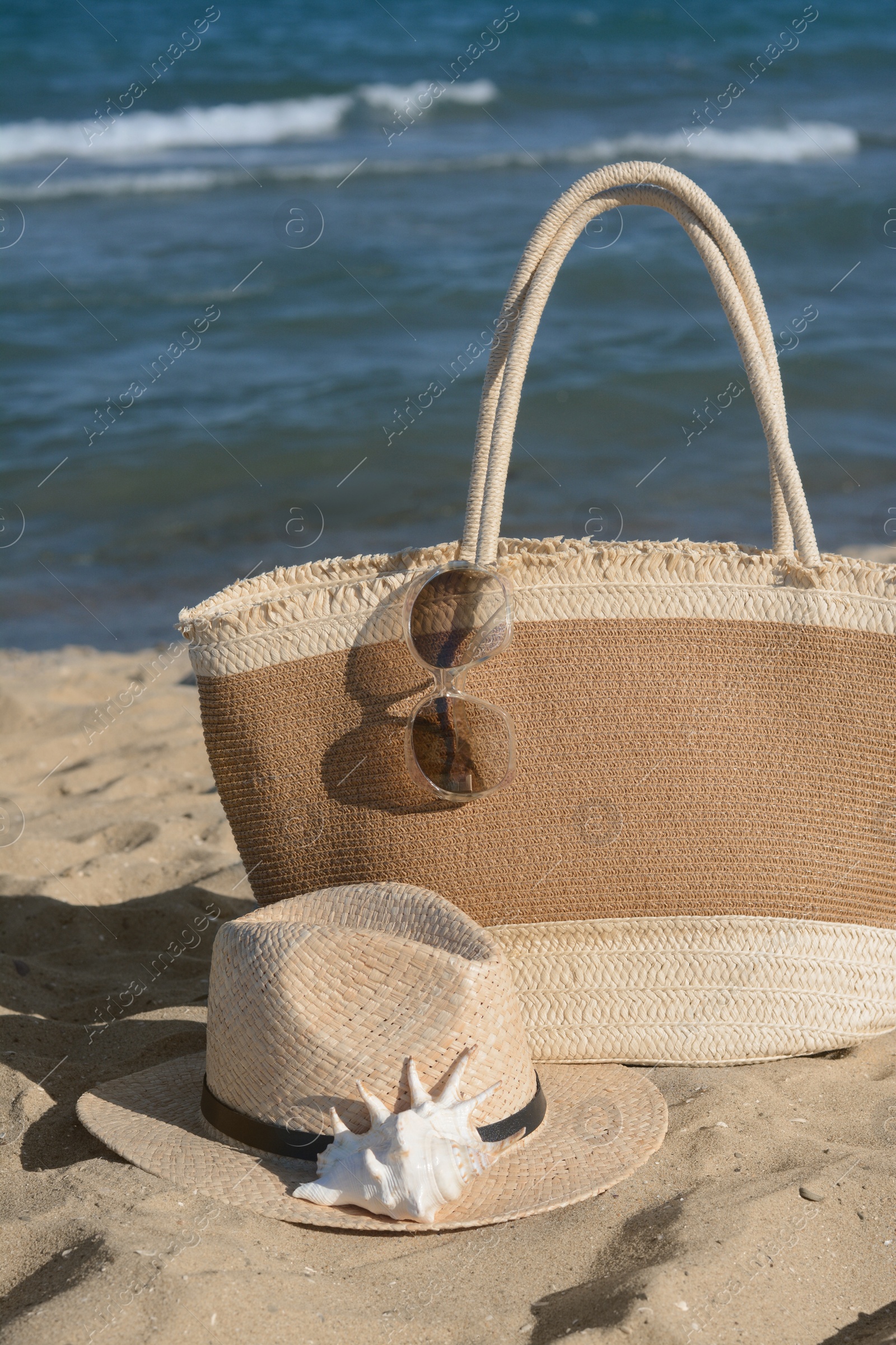 Photo of Stylish bag and other beach accessories near sea on sunny day