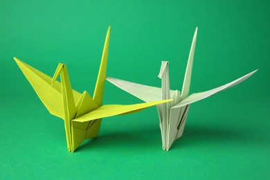 Photo of Paper origami cranes on green background, closeup