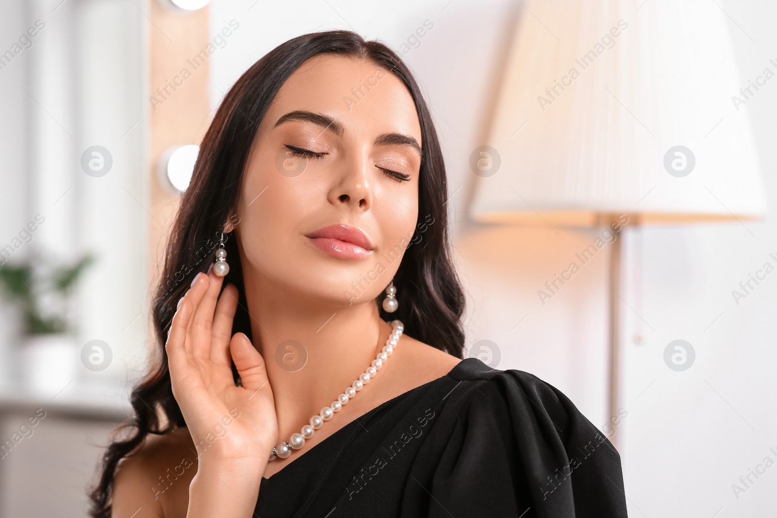 Photo of Young woman wearing elegant pearl jewelry indoors