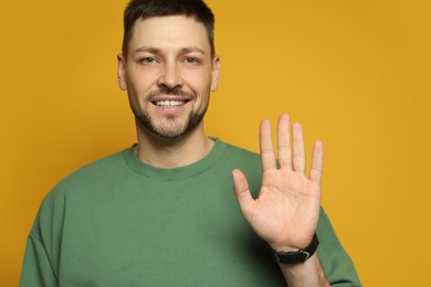 Left-handed man with open palm on yellow background