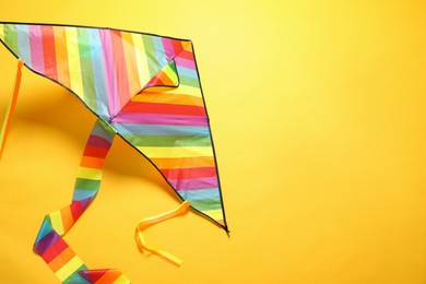 Photo of Bright rainbow kite on yellow background, above view. Space for text
