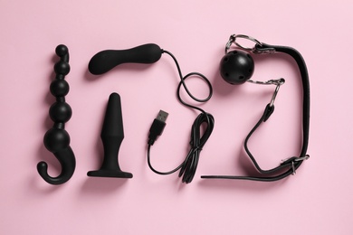 Different sex toys on pink background, flat lay