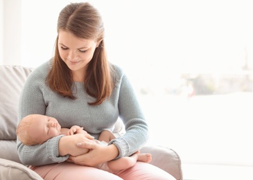 Photo of Young mother with her newborn baby in armchair at home