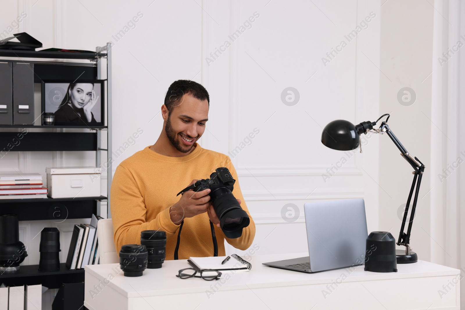 Photo of Young professional photographer with camera at table in modern photo studio