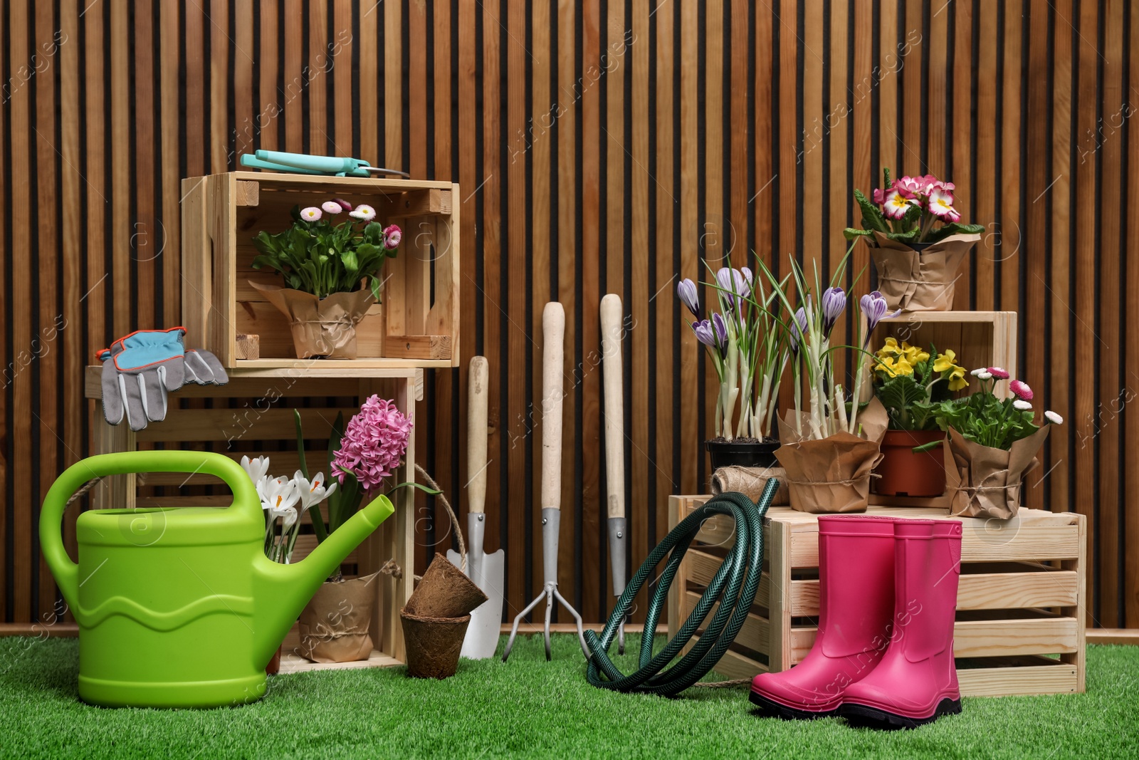 Photo of Composition with different gardening tools on artificial grass at wooden wall