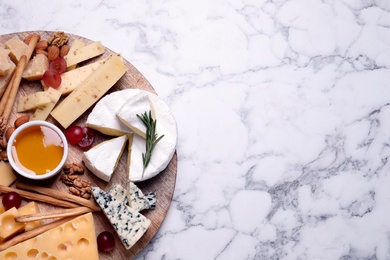 Photo of Cheese plate with honey, grapes and nuts on white marble table, top view. Space for text