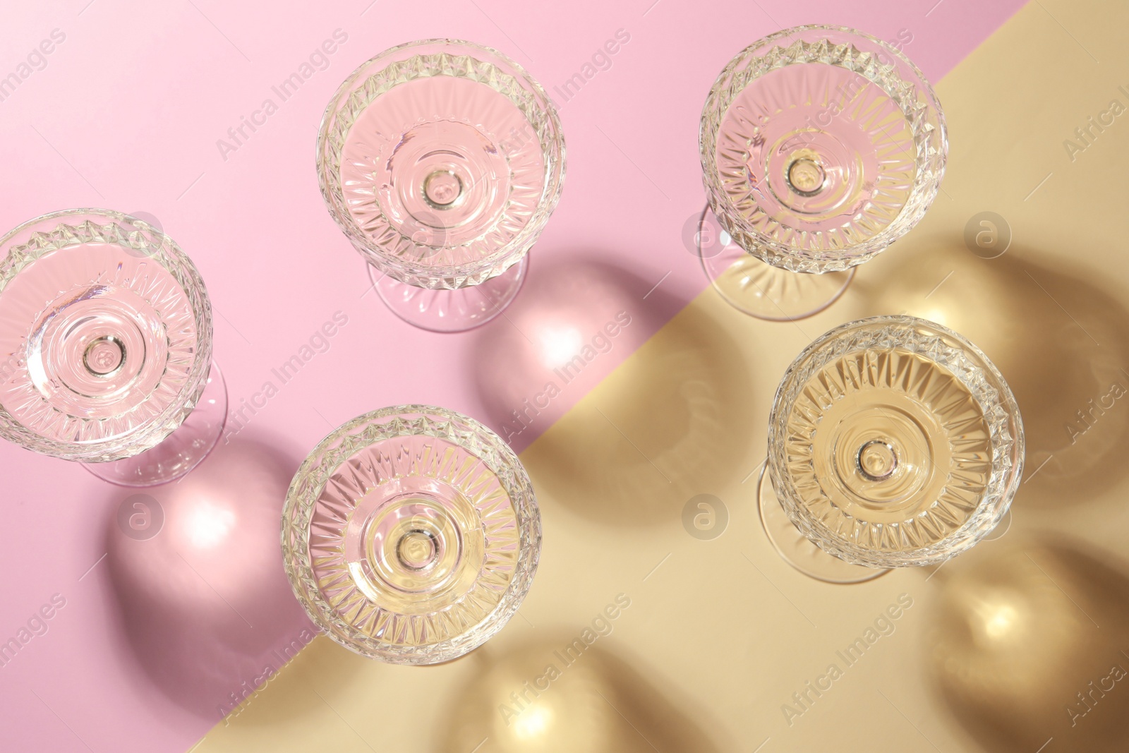 Photo of Glasses of expensive white wine on color background, flat lay