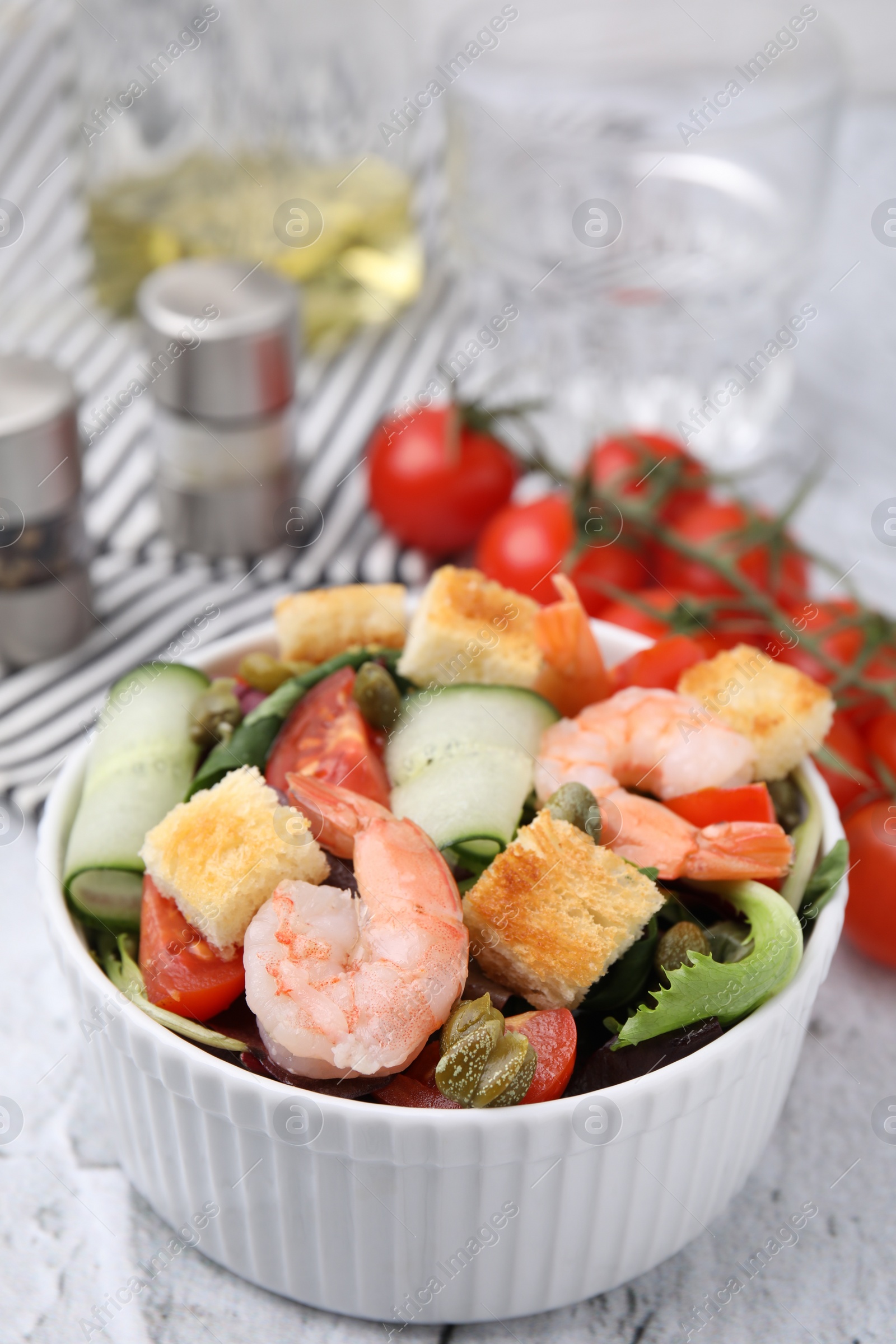 Photo of Tasty salad with croutons, tomato and capers on white textured table, closeup