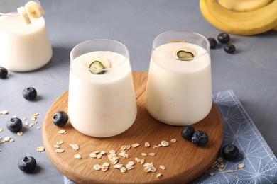 Photo of Tasty yogurt in glasses, oats and blueberries on grey table