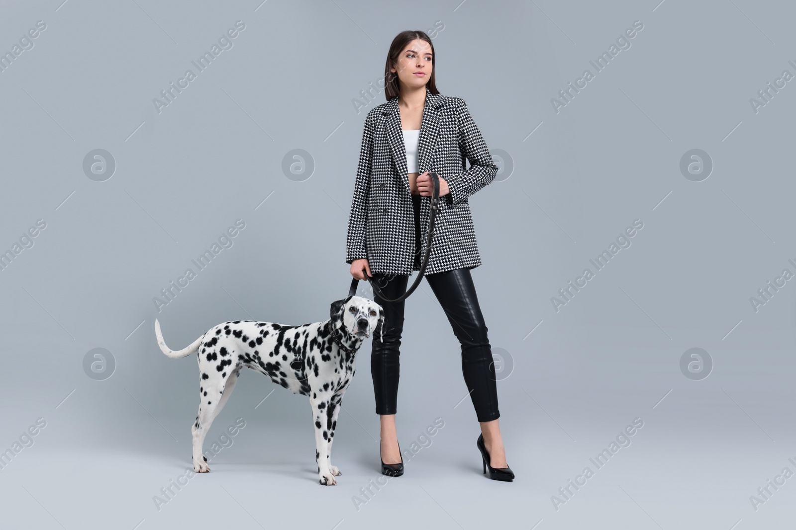 Photo of Beautiful young woman with her adorable Dalmatian dog on light grey background. Lovely pet