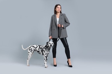 Photo of Beautiful young woman with her adorable Dalmatian dog on light grey background. Lovely pet