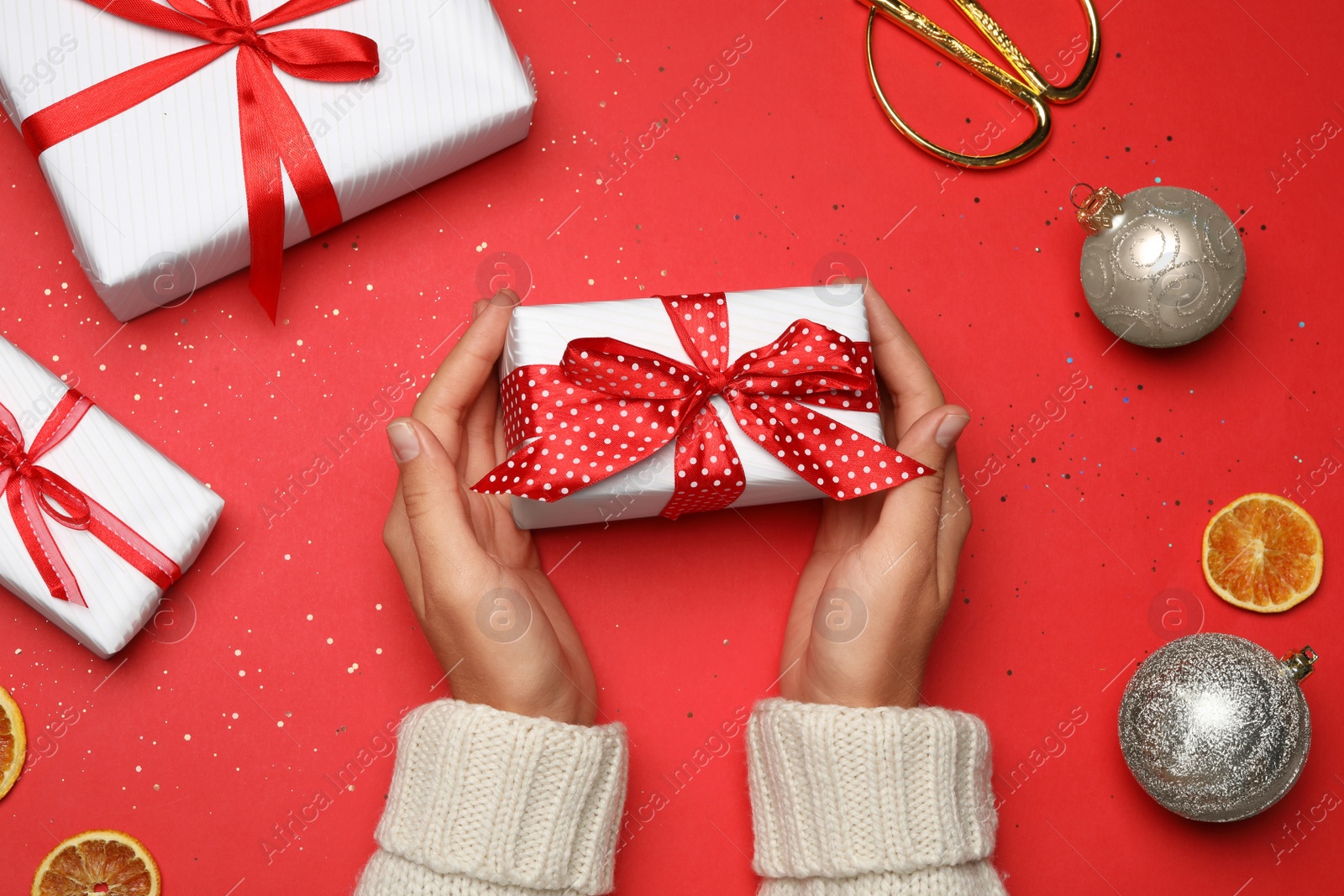 Photo of Young woman holding Christmas gift on red background, flat lay