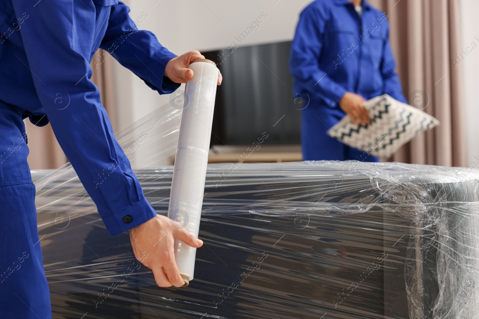 Photo of Male movers with sofa and pillow in new house, closeup