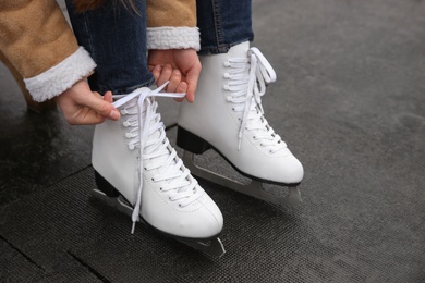 Photo of Woman lacing figure skate outdoors, closeup view