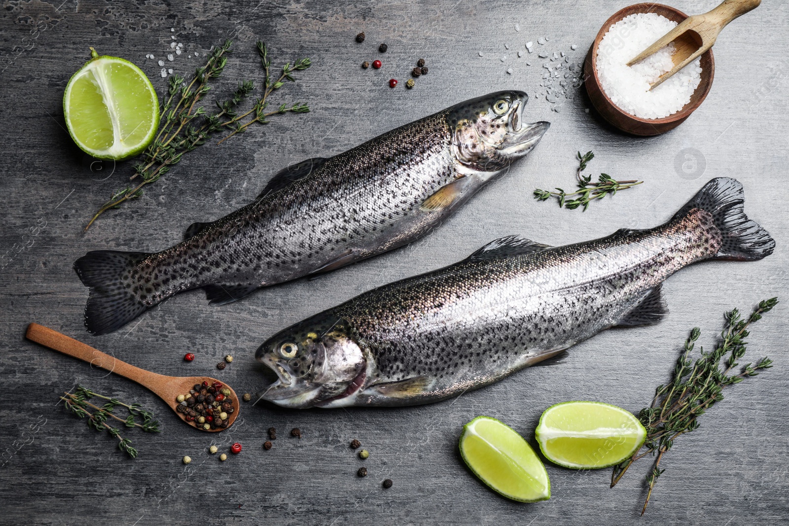 Photo of Flat lay composition with raw cutthroat trout fish on grey table