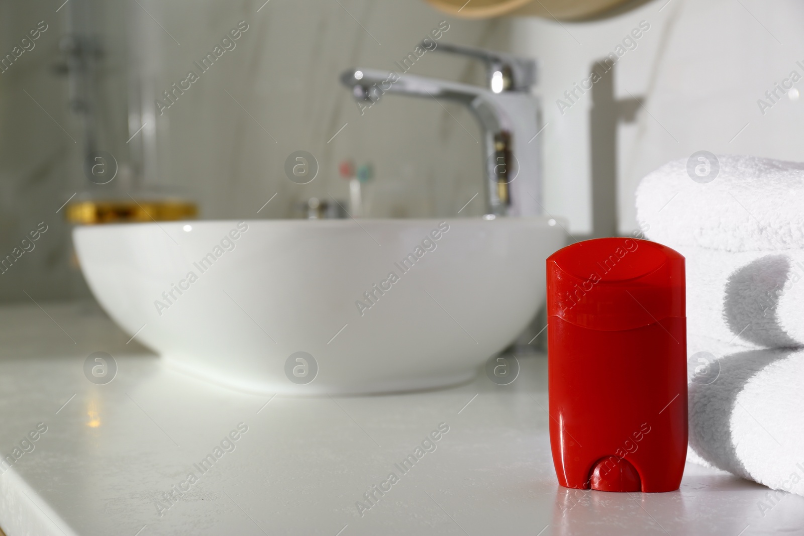 Photo of Deodorant with clean towels on countertop in bathroom