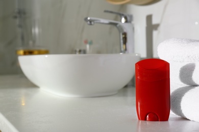 Photo of Deodorant with clean towels on countertop in bathroom