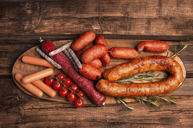 Different tasty sausages on wooden table, top view