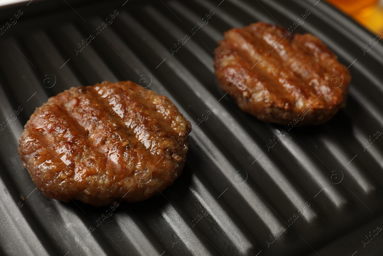 Photo of Delicious hamburger patties on electric grill, closeup