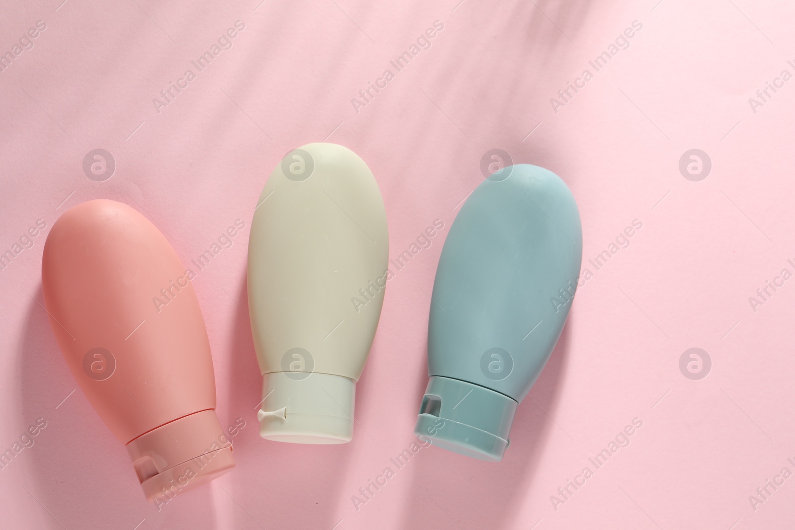 Photo of Cosmetic travel kit on pink background, top view