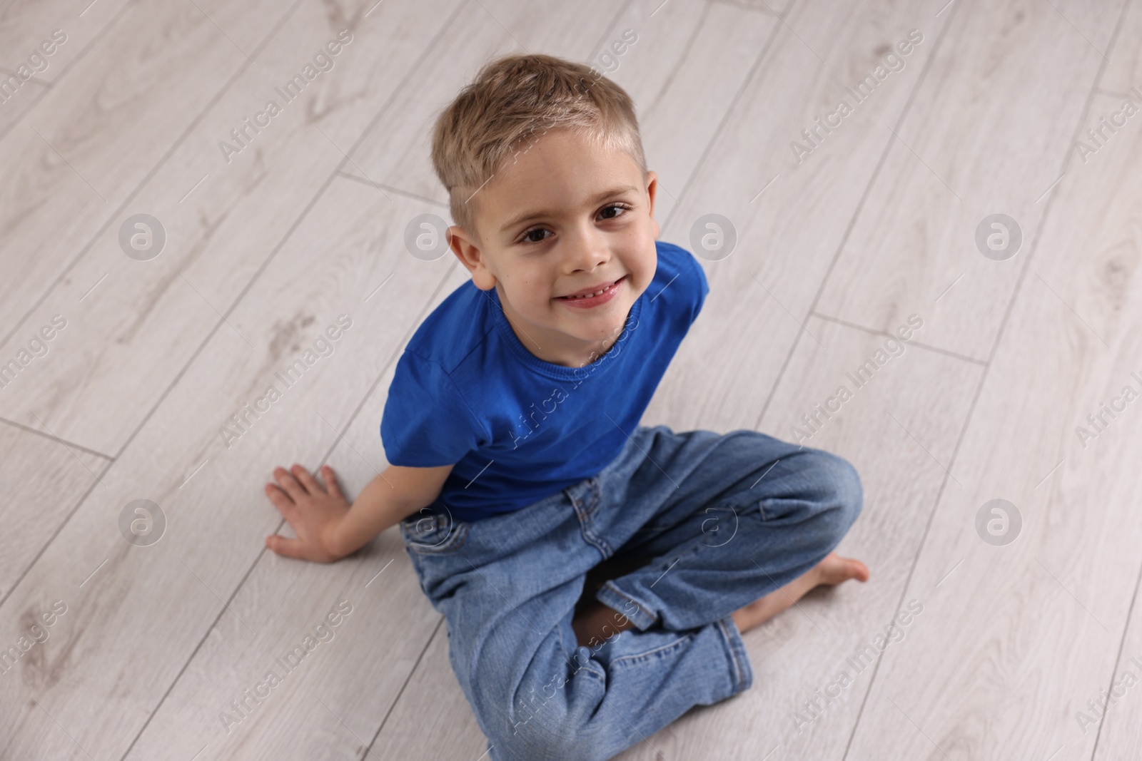 Photo of Cute little boy sitting on warm floor indoors. Heating system