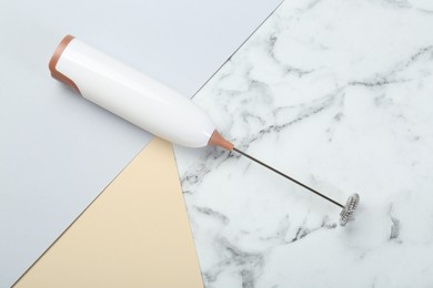 Photo of White milk frother wand on color background, top view