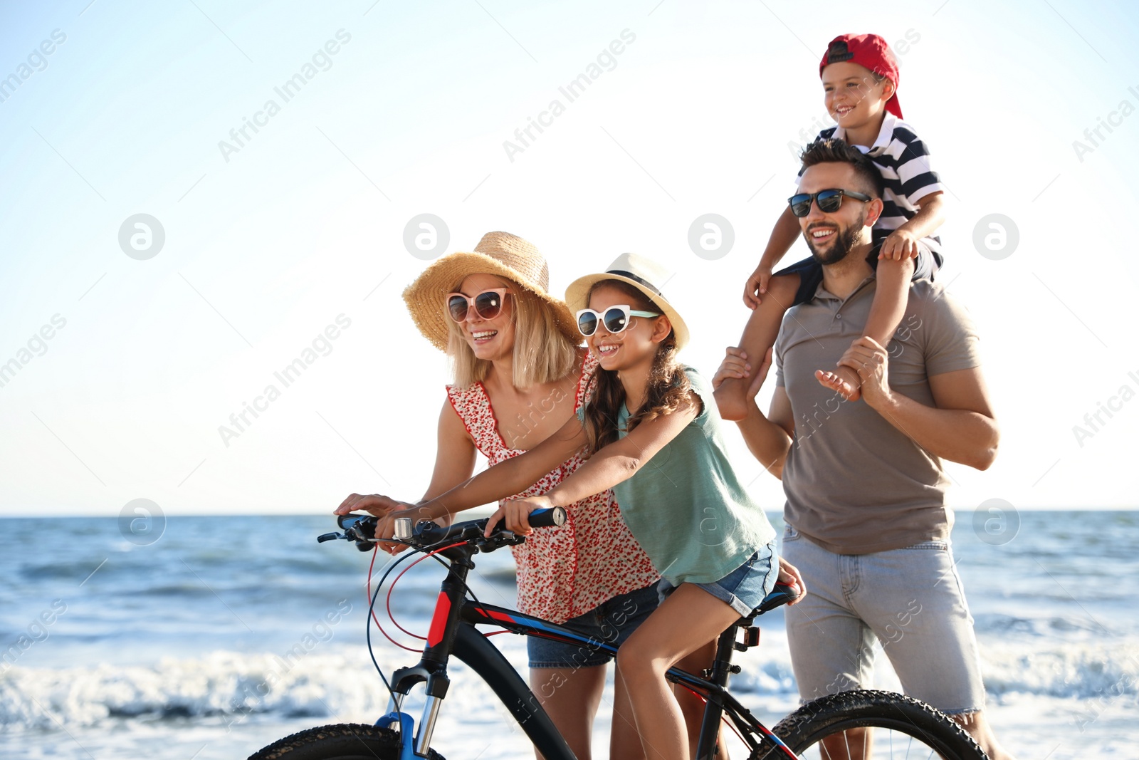 Photo of Happy family with bicycle on beach near sea