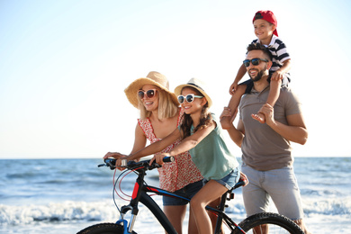 Happy family with bicycle on beach near sea