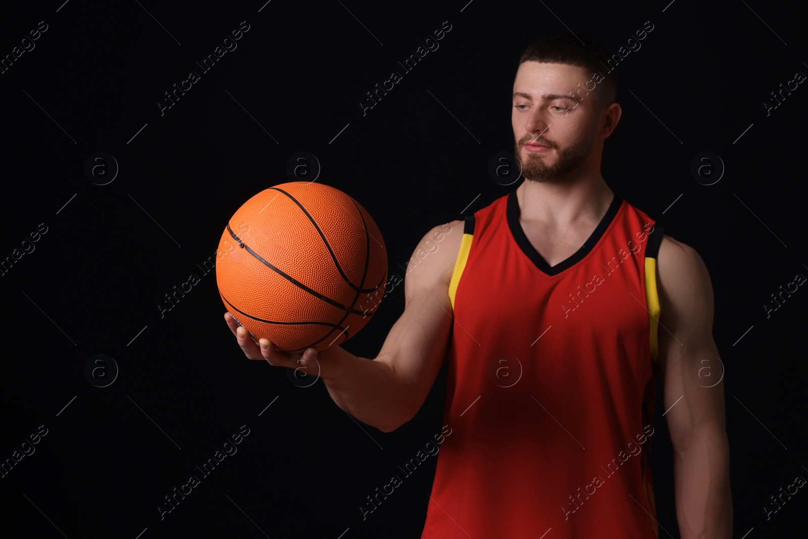 Photo of Athletic young man with basketball ball on black background