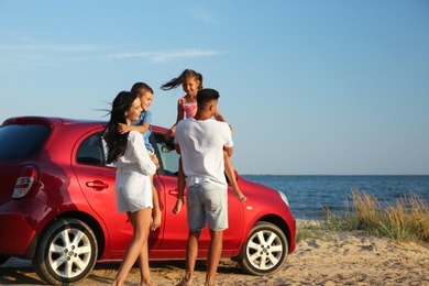 Photo of Happy family near car on sandy beach. Summer trip