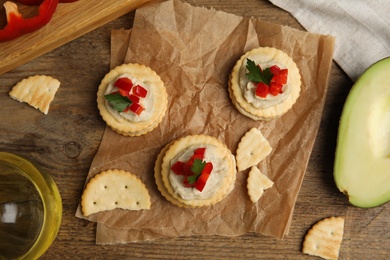 Photo of Delicious crackers with humus, bell pepper and parsley on wooden table, flat lay