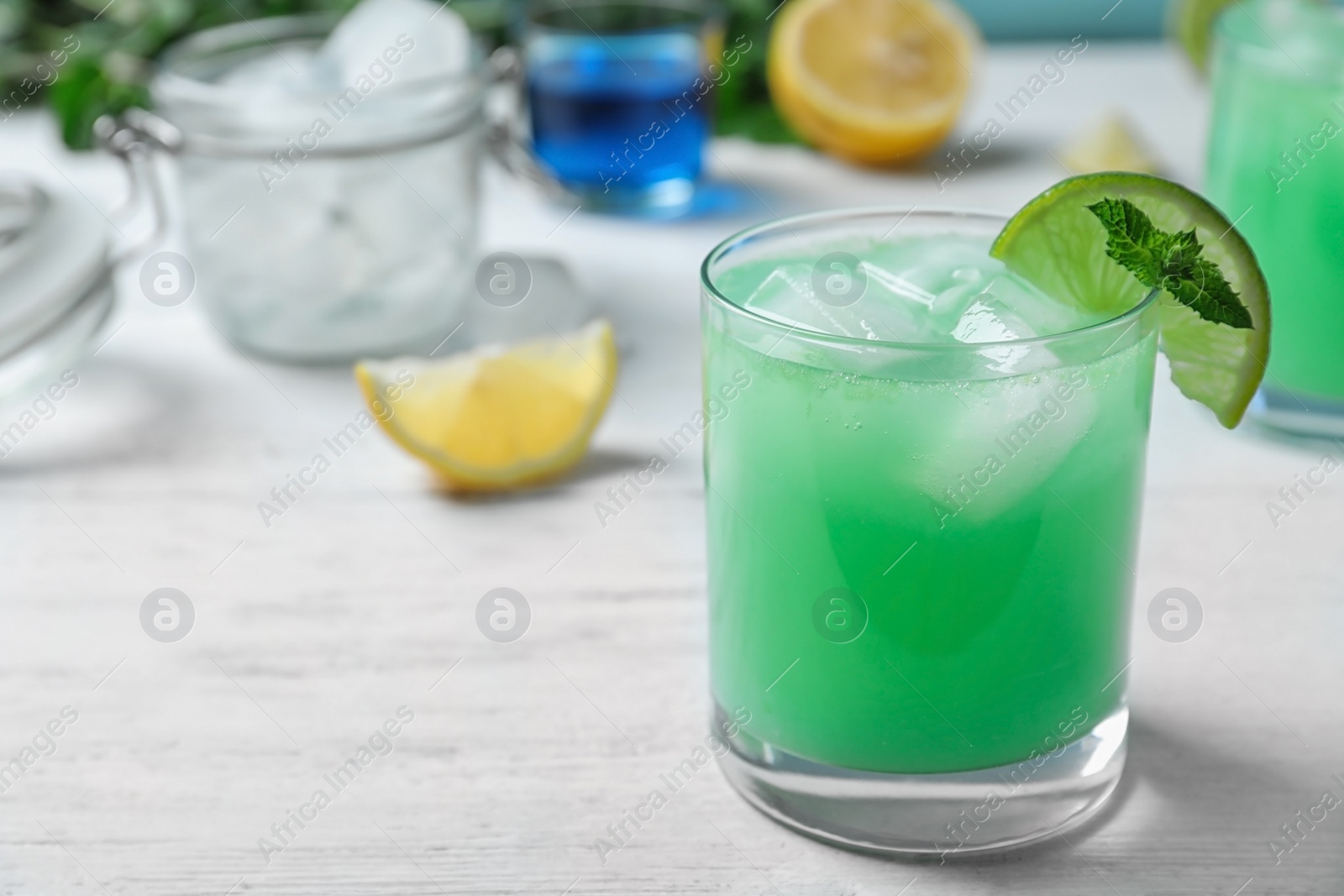 Photo of Glass of delicious cocktail with ice on white wooden table. Space for text