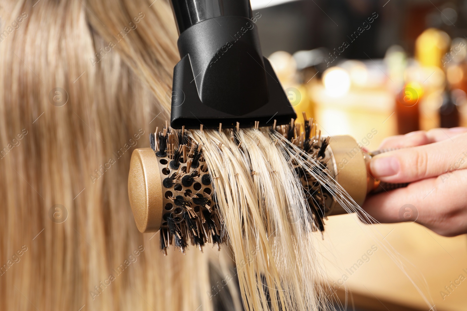 Photo of Hairdresser blow drying client's hair in salon, closeup