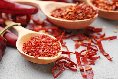 Spoons with chili pepper flakes on table, closeup