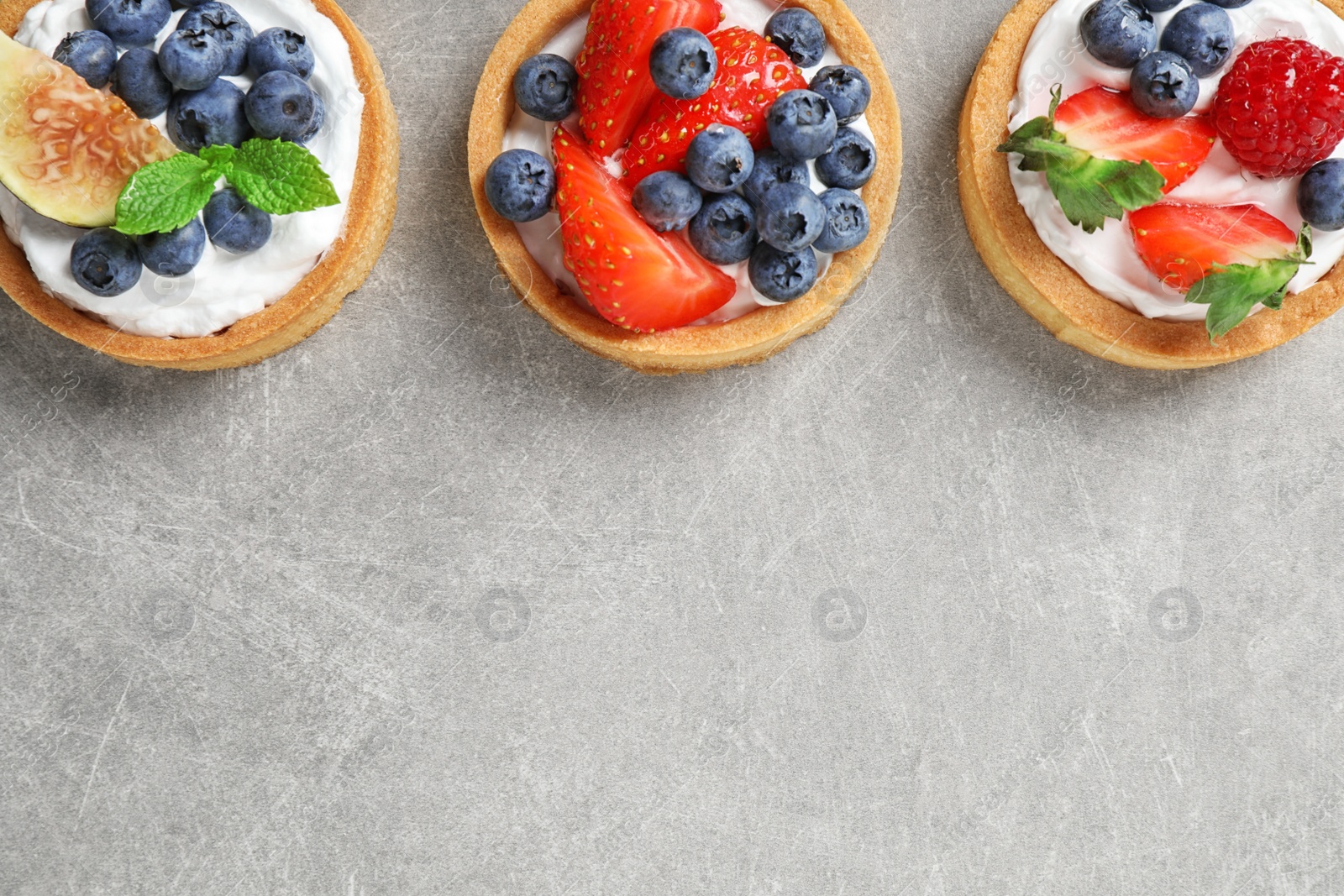 Photo of Delicious sweet pastries with berries on grey table, flat lay. Space for text