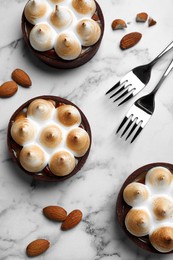 Delicious salted caramel chocolate tarts with meringue and almonds on white marble table, flat lay