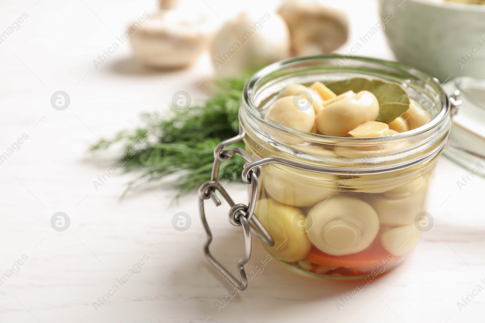 Photo of Jar with marinated mushrooms on white wooden table, closeup. Space for text