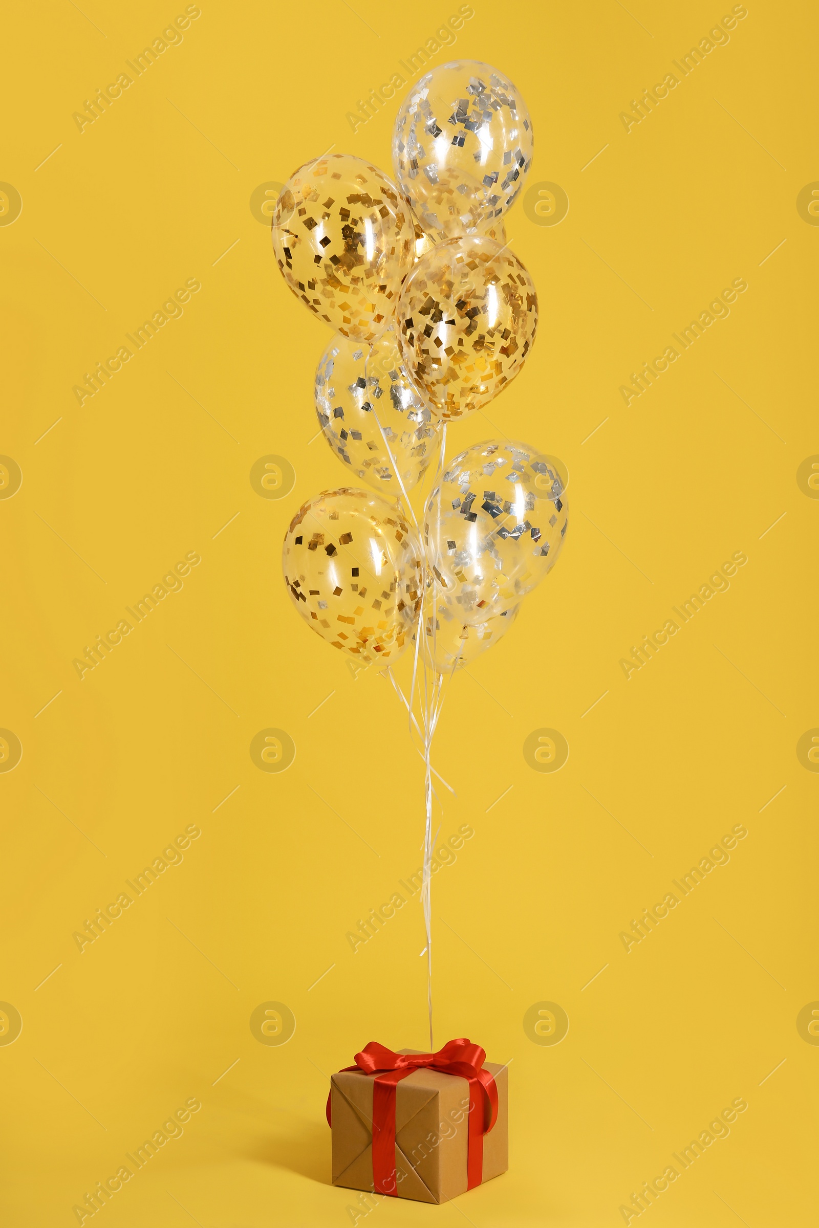 Photo of Bright balloons and gift box on color background