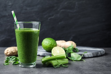 Green juice and fresh ingredients on grey table. Space for text