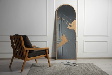 Photo of Broken mirror with many cracks and armchair in room