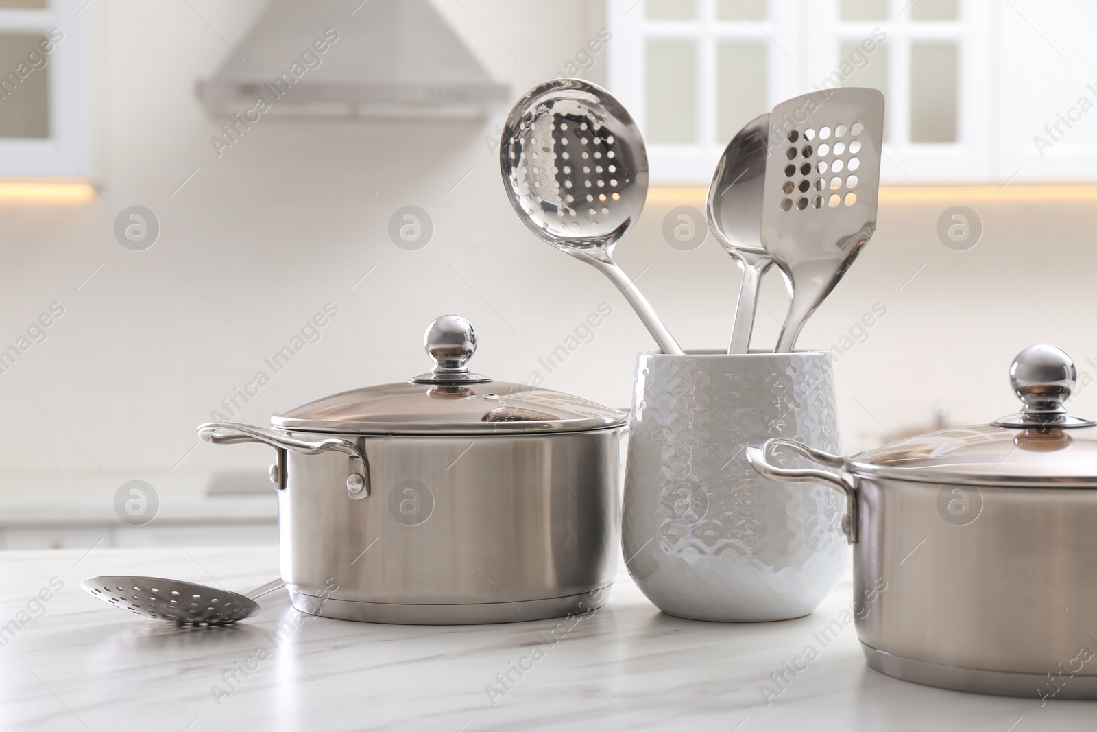 Photo of Stainless steel pots and kitchen utensils on white table indoors