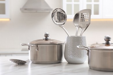 Photo of Stainless steel pots and kitchen utensils on white table indoors