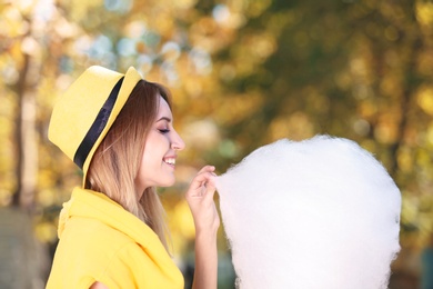 Photo of Young cheerful woman having fun with  cotton candy in park