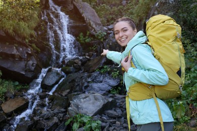 Photo of Tourist with backpack near waterfall in mountains. Space for text
