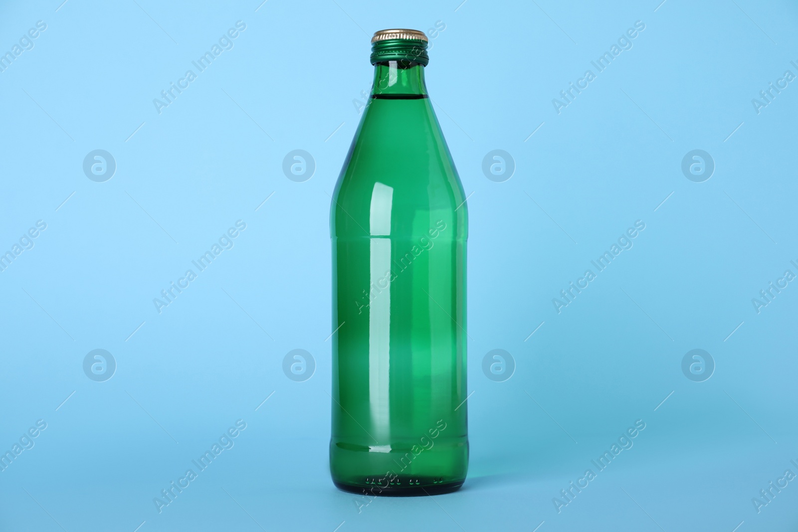 Photo of Glass bottle with water on light blue background