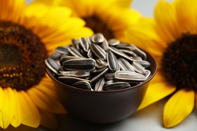 Photo of Raw sunflower seeds and flowers on table, closeup